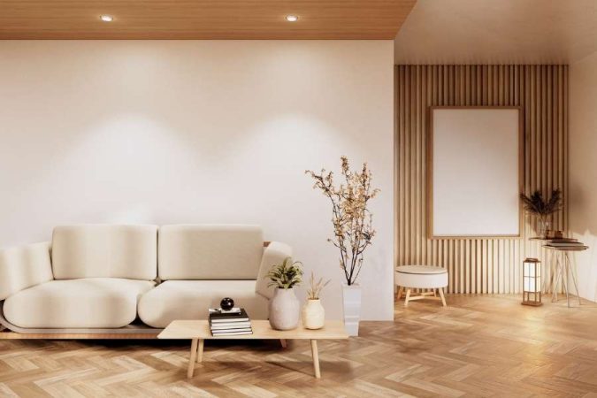 Salon minimaliste aux influences japonaises mettant en valeur différents styles décoratifs avec des tons bois naturels et un canapé crème.
