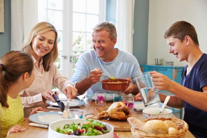 Repas de famille : une famille sourit en partageant un déjeuner convivial autour d'une table bien garnie.